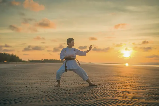 Pratiquant d’arts martiaux sur une plage au coucher du soleil