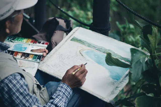 Mains qui peignent une aquarelle dans un carnet