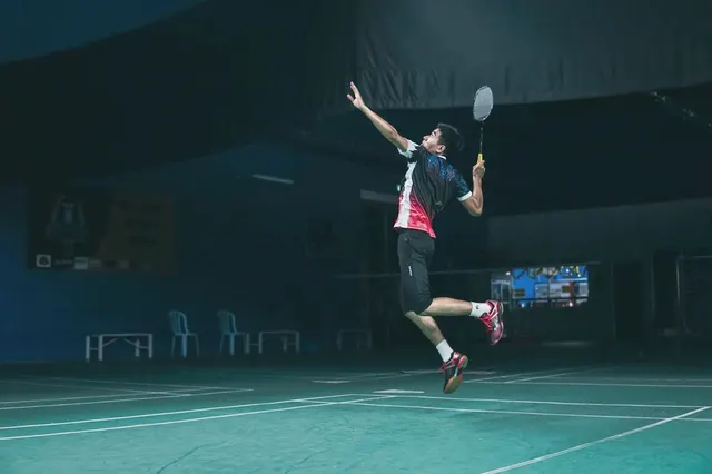 Joueur de badminton en suspension pour un smash, dans un gymnase