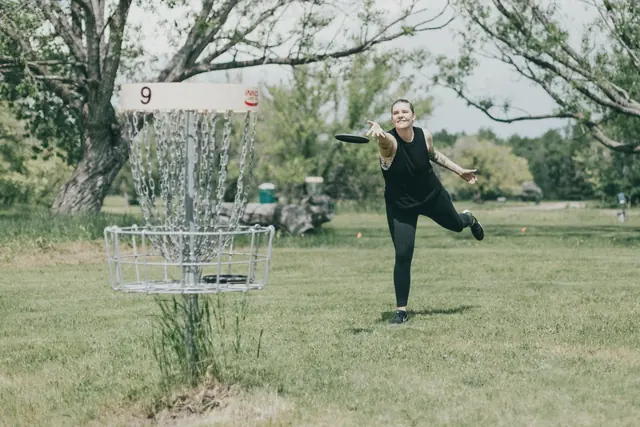 Joueur qui lance un disque vers une corbeille de disc-golf