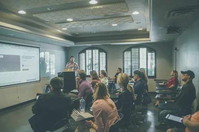 Salle de cours pleine d’adultes face à un écran de présentation