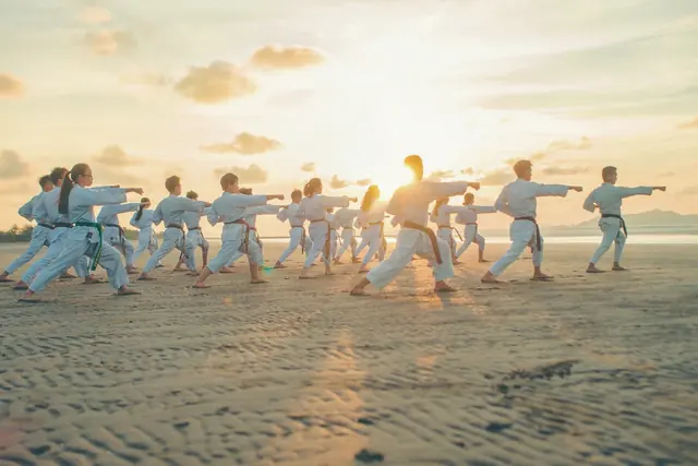 Groupe d’arts martiaux sur une plage au lever du jour
