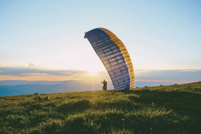 Parapente au décollage sur une pente au coucher du soleil
