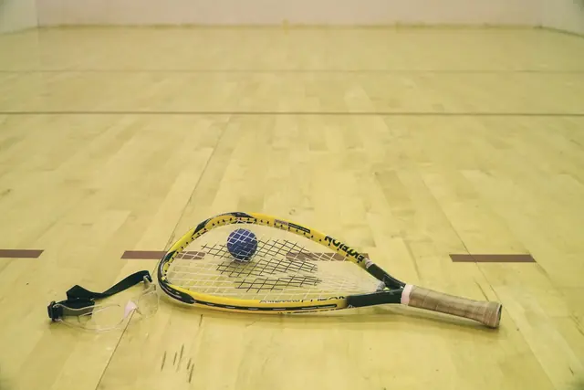 Raquette et balle de squash sur le parquet du court